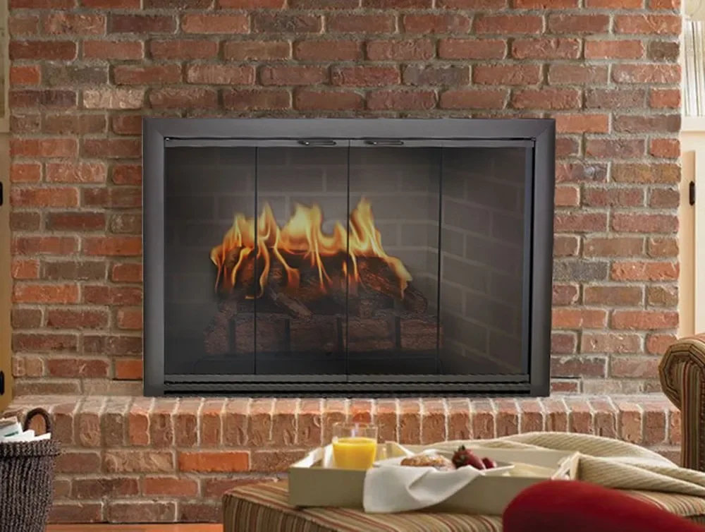 A cozy living room with a brick fireplace containing a fire with flames, a tray with a glass of orange juice, and a plate of food on a striped sofa armrest.