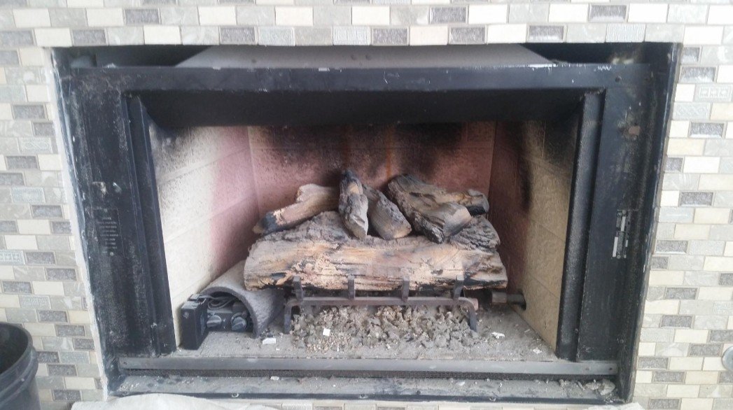 A fireplace with logs and ash inside.