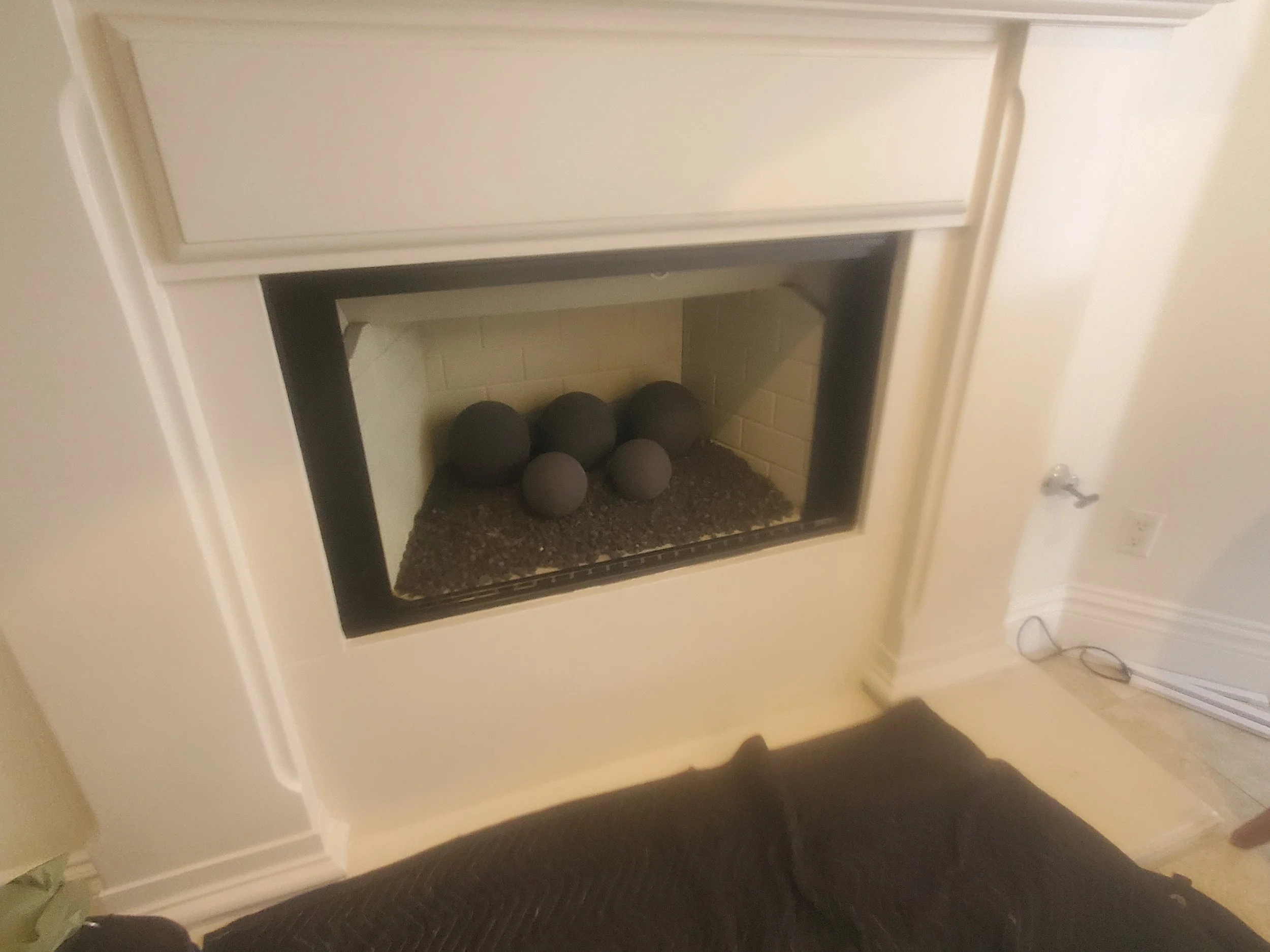 Living room fireplace with black decorative stones inside.