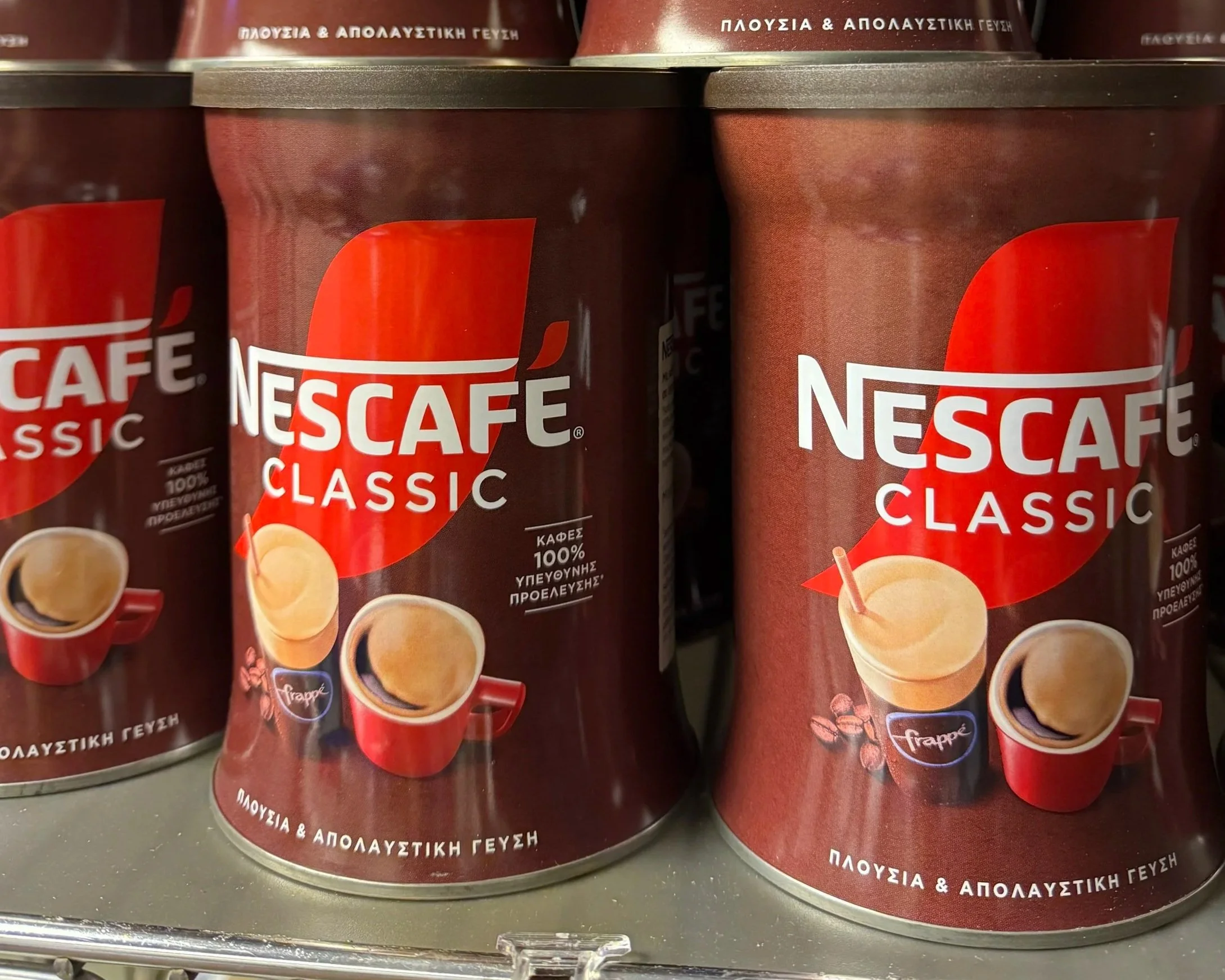 Tins of Greek Nescafé Classic on a store shelf.