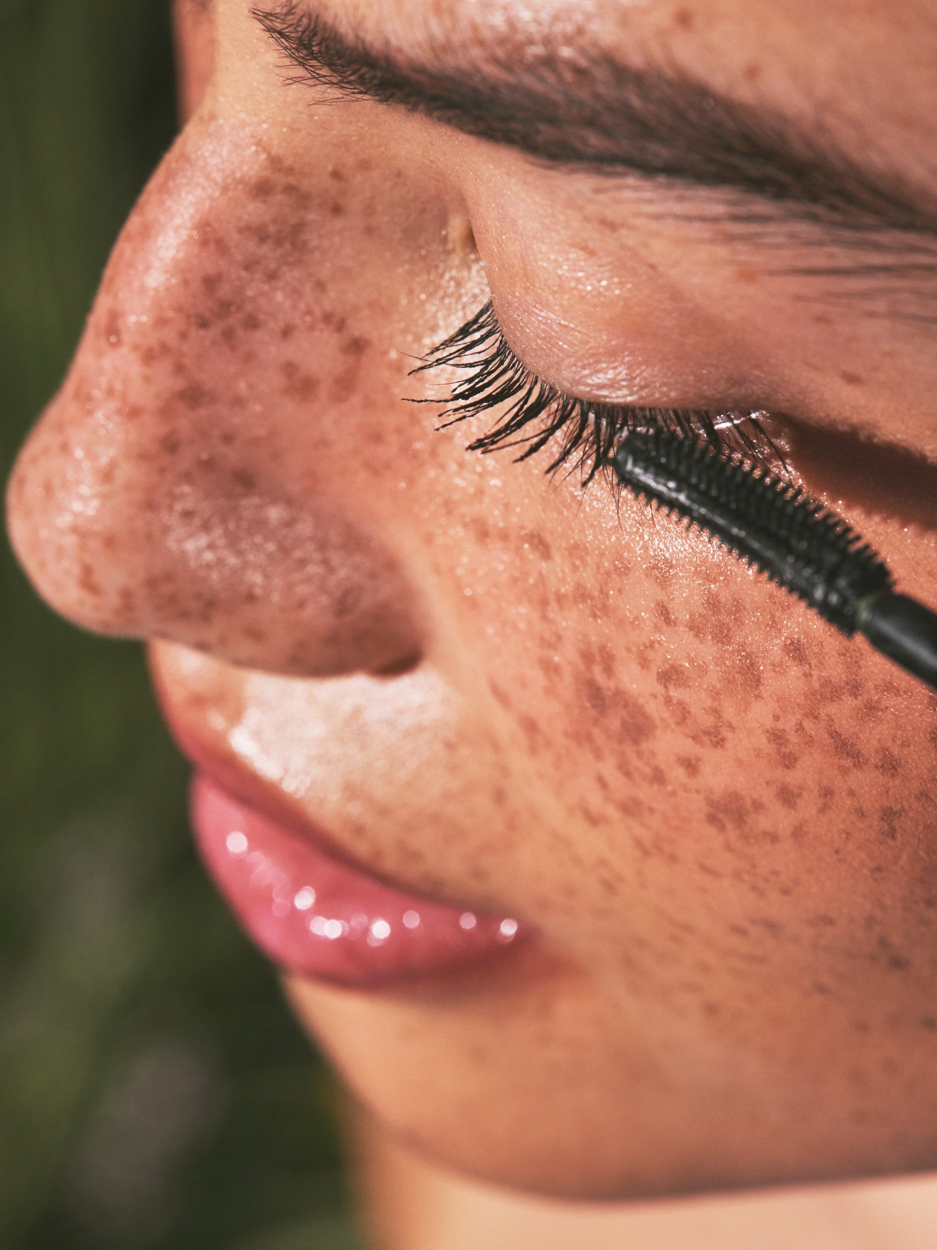 Joshua Pestka commercial beauty photography — Well People Skinphoria campaign, extreme close-up of freckled skin with mascara lash detail and pink lip