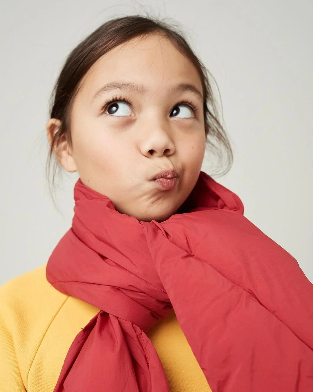 Joshua Pestka kids fashion photography — girl in yellow top with red scarf, playful expression, close-up portrait