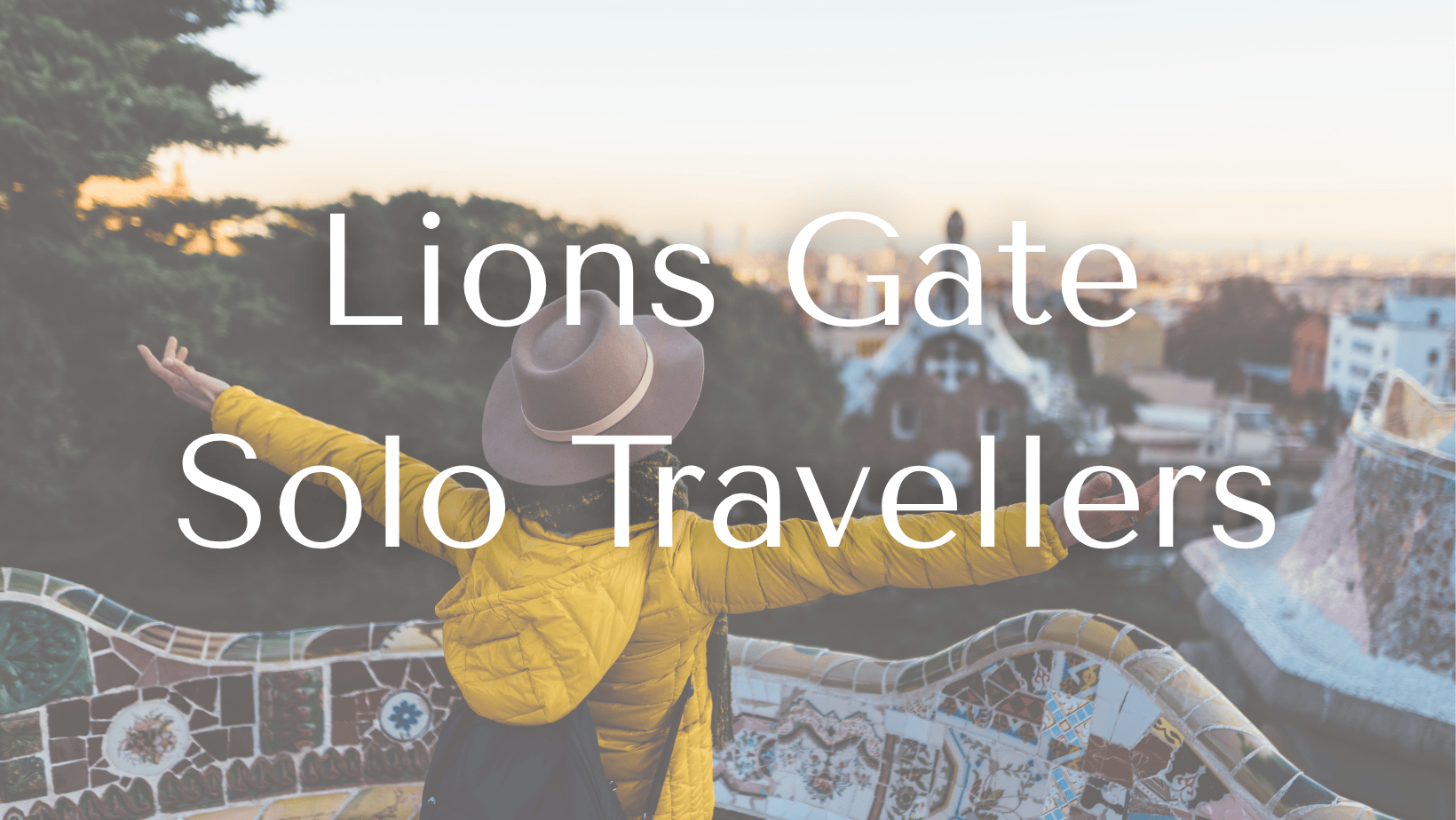 Person with arms outstretched standing on a colorful mosaic bench in Park Güell in Barcelona, Spain, overlooking the city skyline during sunset. Facebook group for solo travellers.