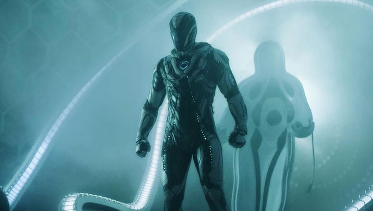 Two humanoid characters in futuristic suits standing inside a glowing tunnel. The character in the foreground has a sleek, black, armored suit with a helmet, while the background character wears a white suit with black markings and holds a cable or d