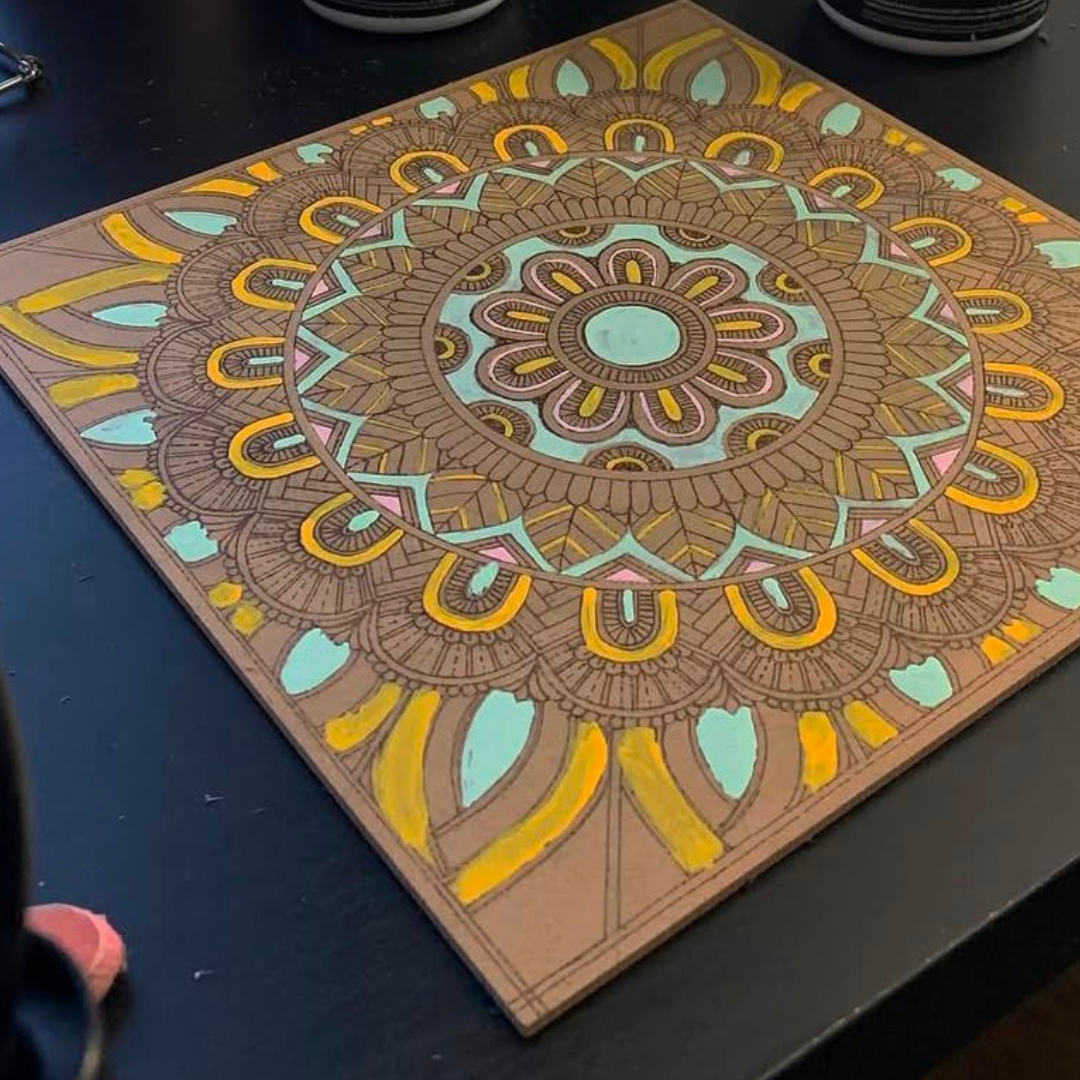 Mandala artwork surrounded by painting supplies during a Sim.err art-making session.