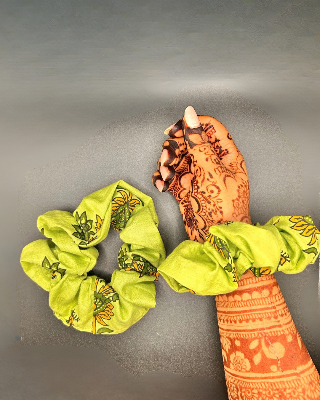 Lime green floral fabric scrunchie displayed beside matching scrunchie worn on wrist