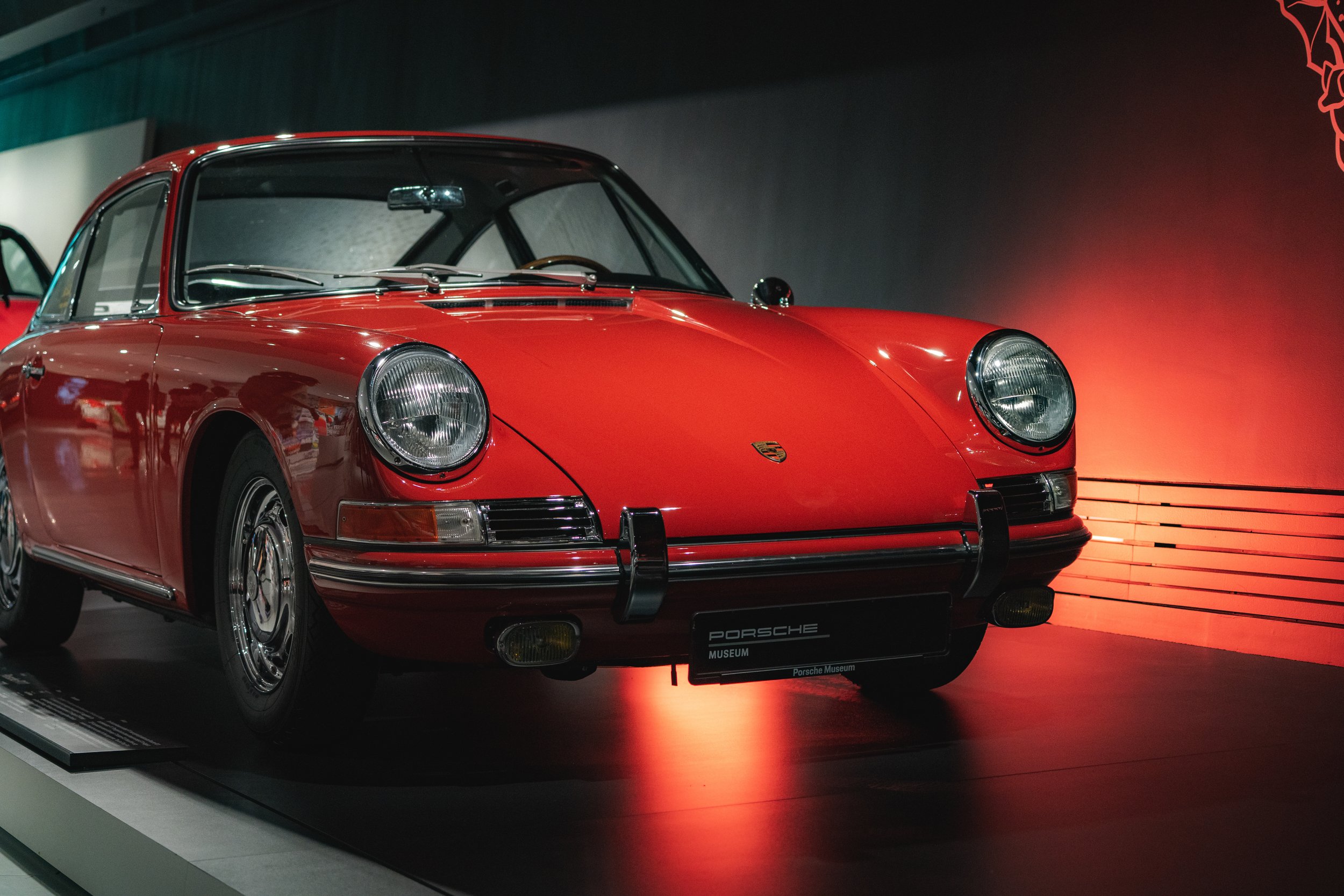 Red classic Porsche 911 sports car on display in a museum with a black background.