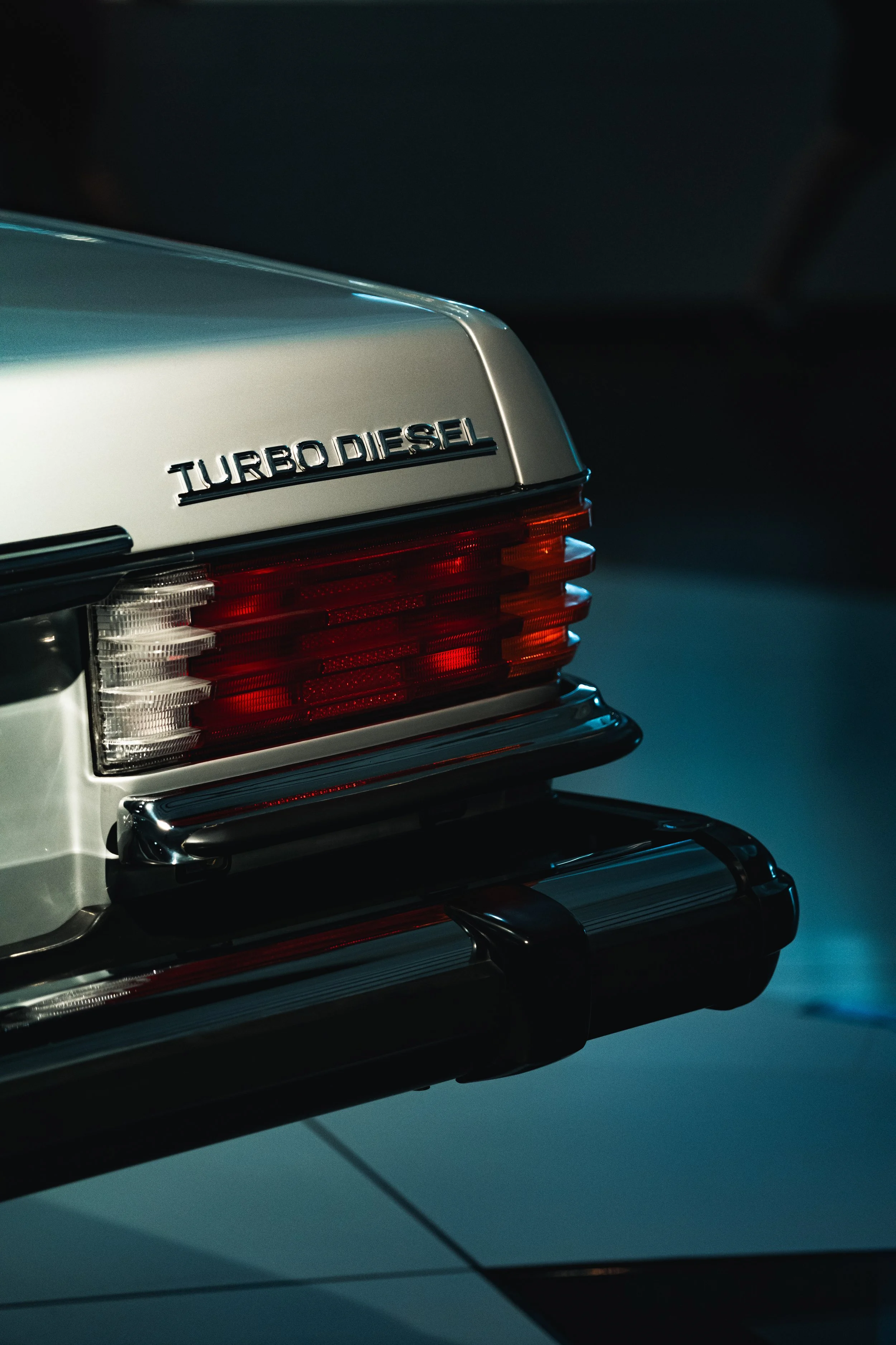 Close-up of the rear of a silver Mercedes-Benz car with a 'Turbo Diesel' badge and red tail lights.