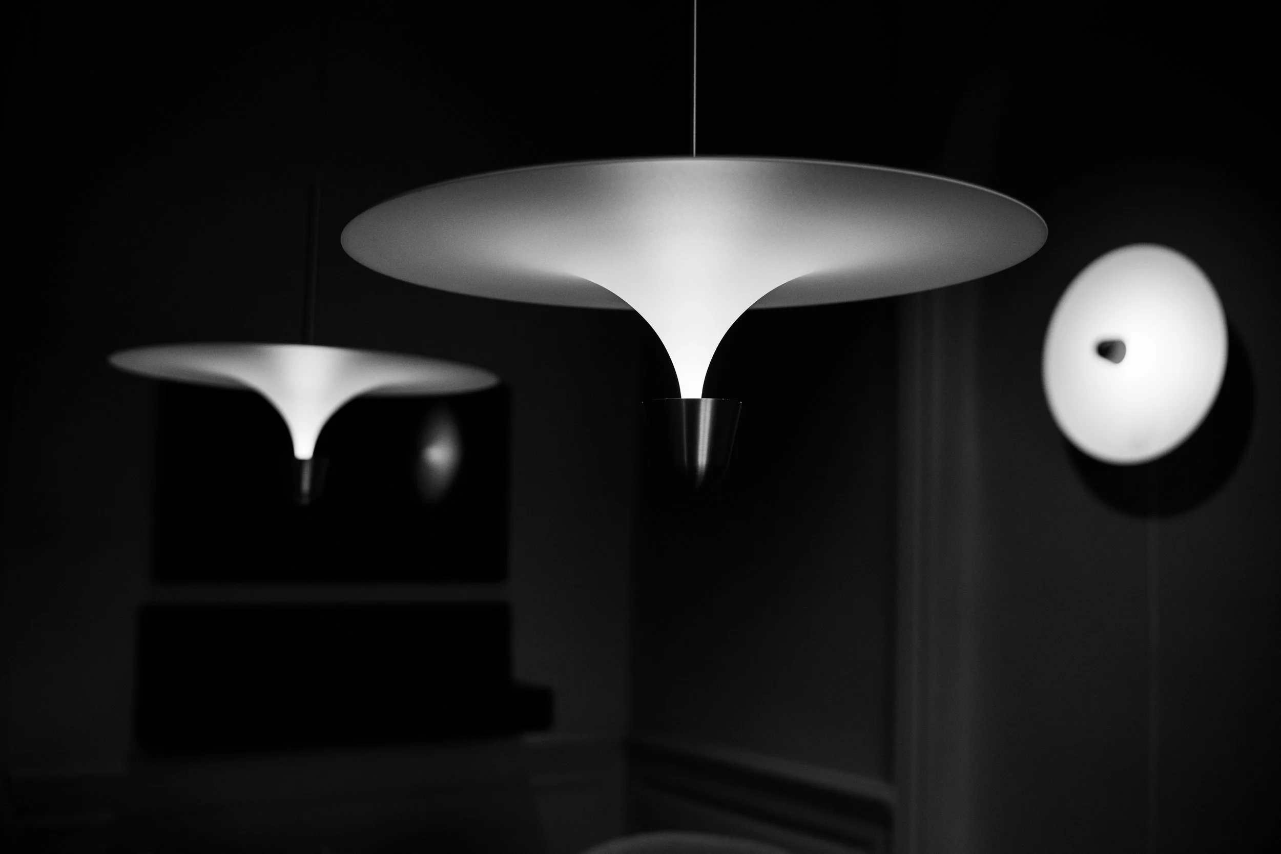 Black and white photograph of modern ceiling lights with disc-shaped shades.