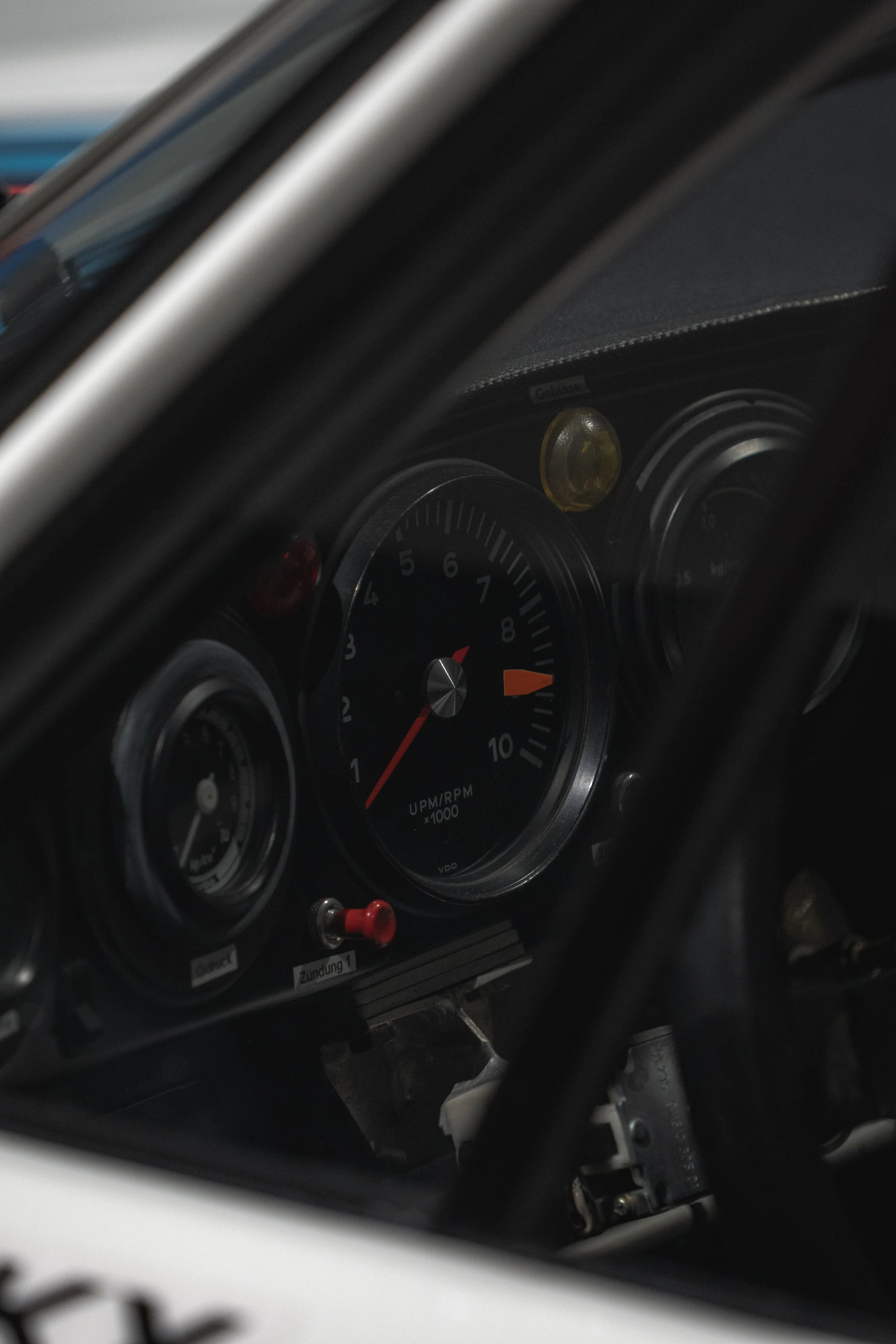 Close-up of a vintage car dashboard showing a tachometer, oil pressure gauge, and warning lights.