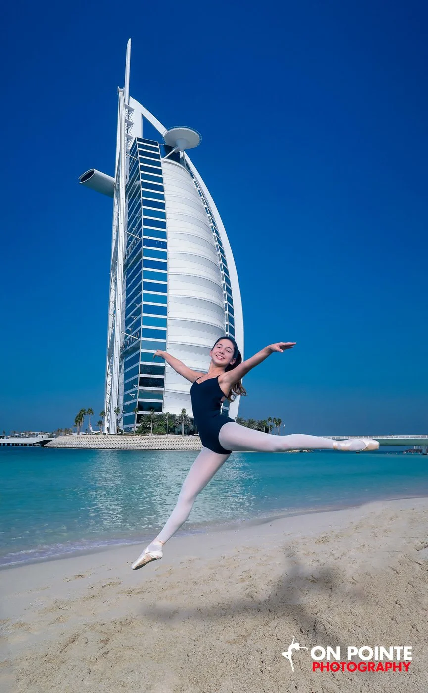 Ballet dancer leaping on a beach with Burj Al Arab in the background.