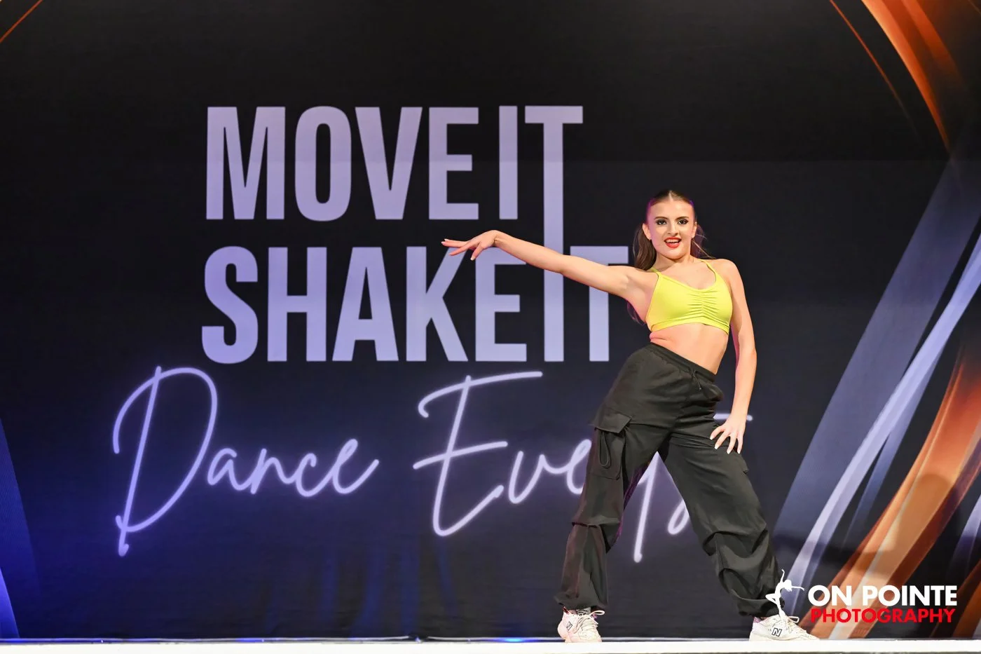 Dancer on stage at "Move It Shake It Dance Event" in yellow top and black pants.