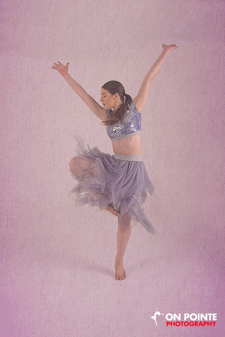 Dancer in mid-air pose wearing a purple outfit on a pink background.