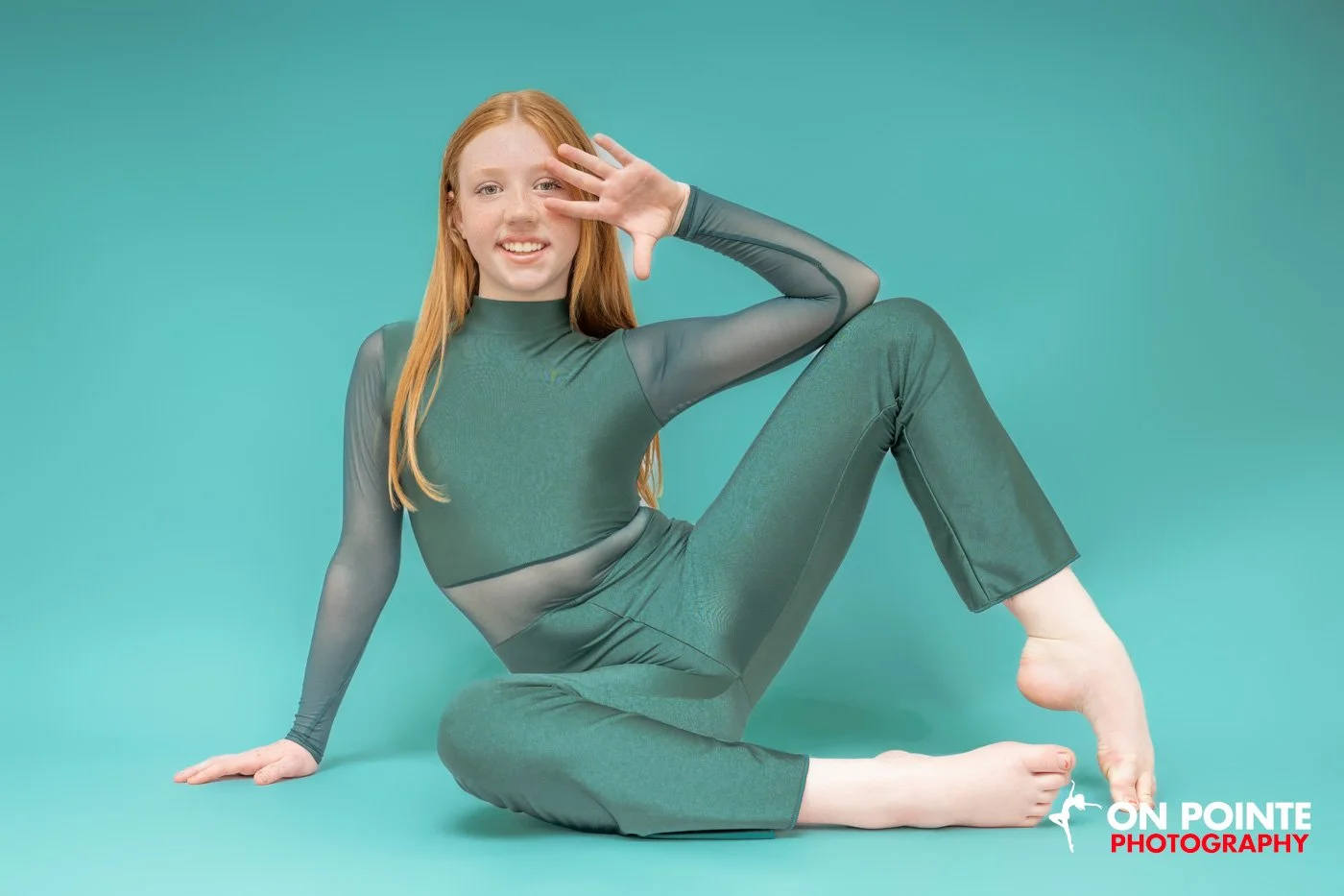 Person in green dance costume posing against a teal background.