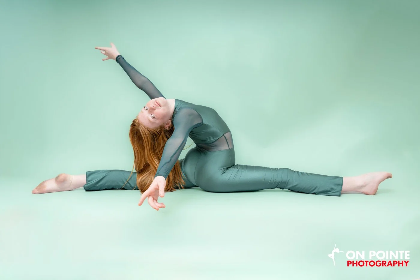 Dancer in green outfit performing split on mint green background