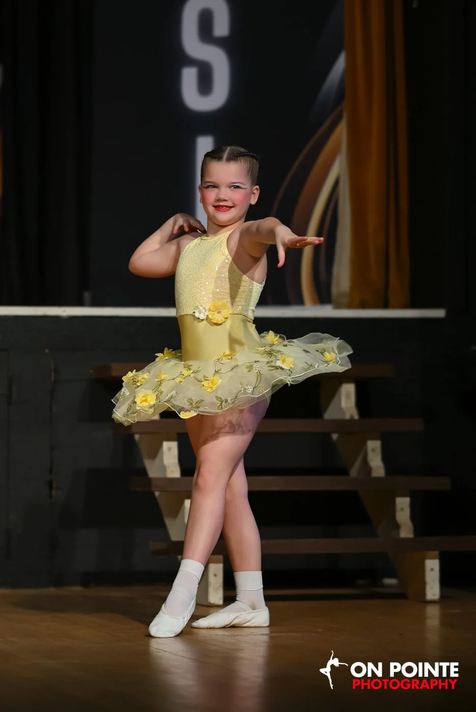 Young girl in a yellow dance costume performing on stage.