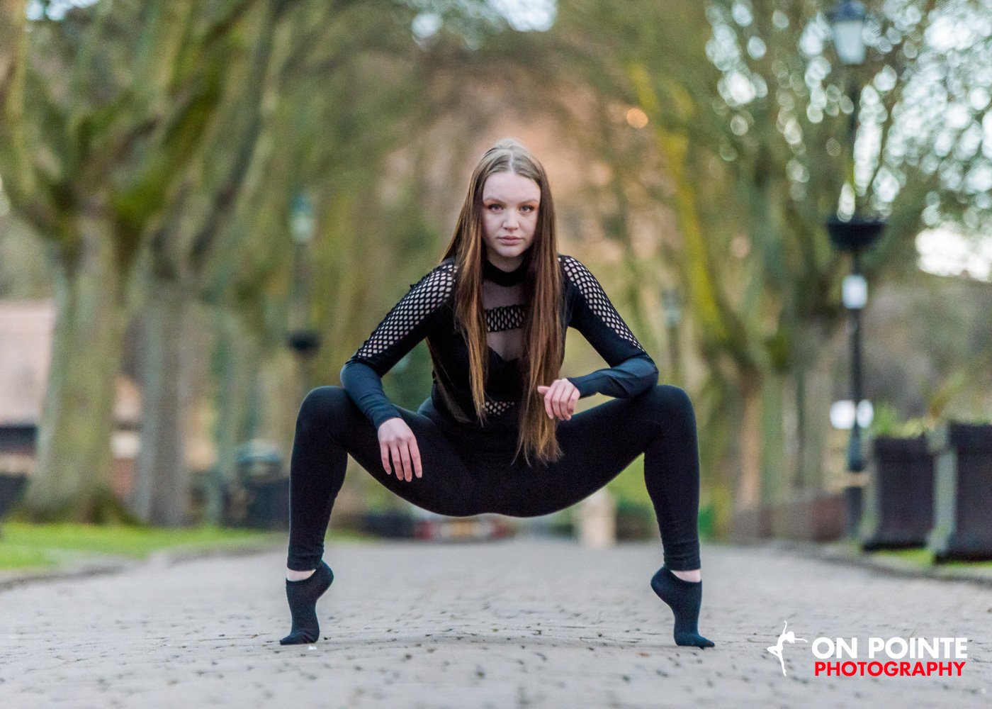 Dancer in black outfit posing on a cobbled street