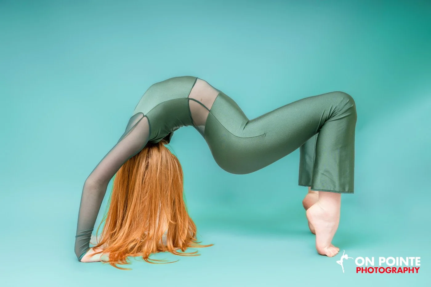 Person in a green bodysuit performing a bridge pose in a studio.