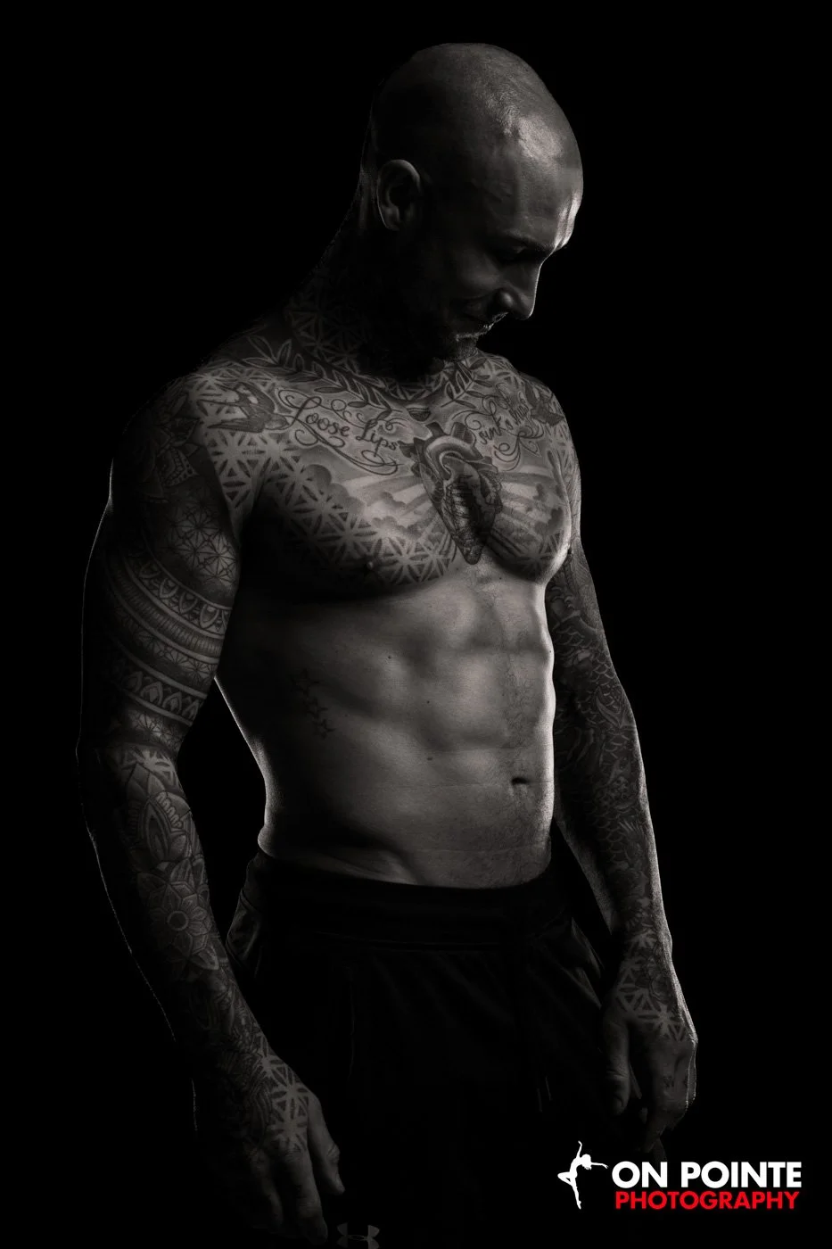 Tattooed muscular man posing shirtless against black background