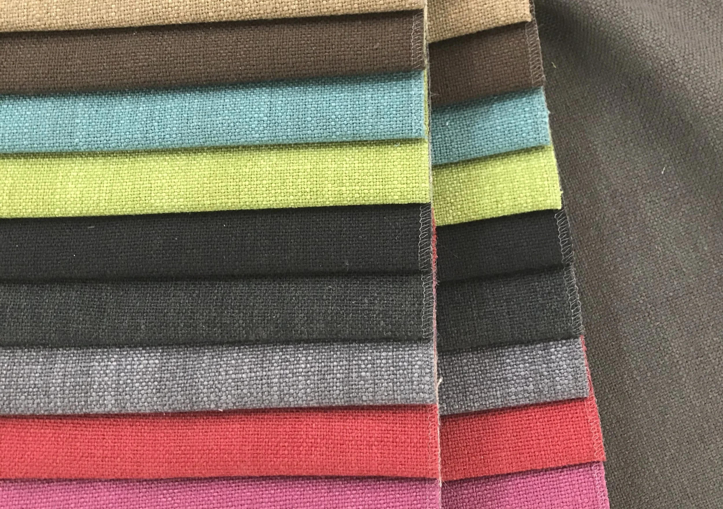 Colorful fabric swatches layered together in shades of brown, blue, green, black, gray, red, and pink.