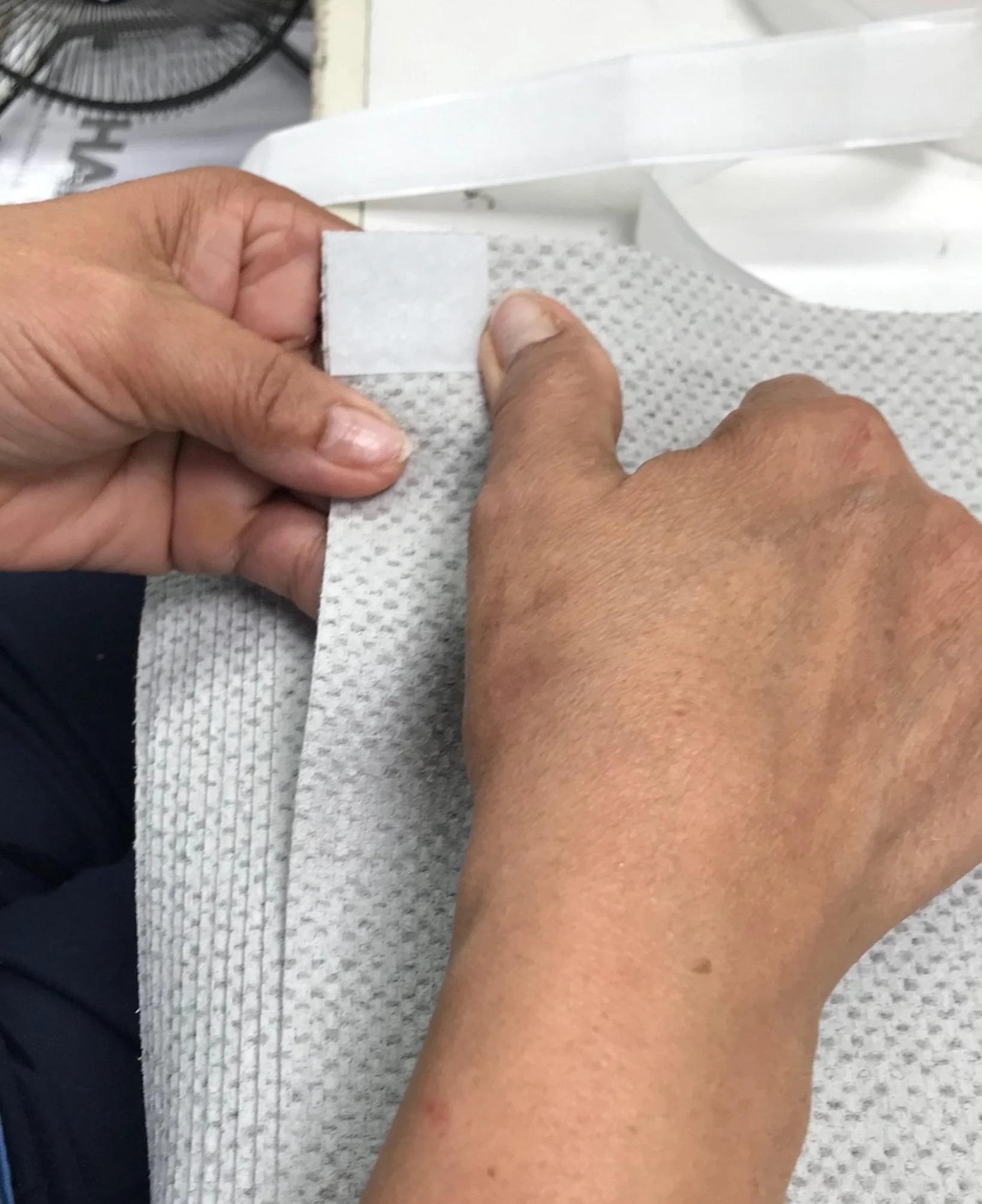 Close-up of hands attaching Velcro tape to gray fabric