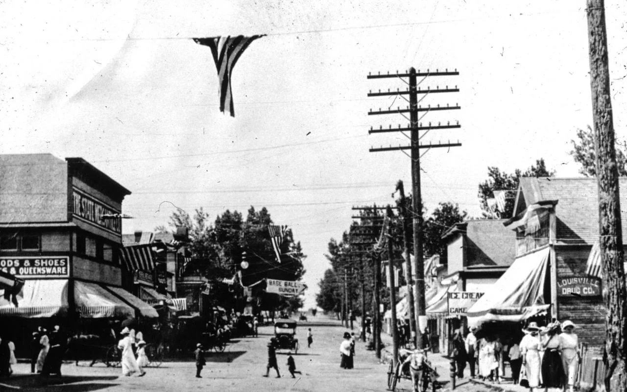 Historic Main Street in Louisville, Colorado with local storefronts and mature trees.