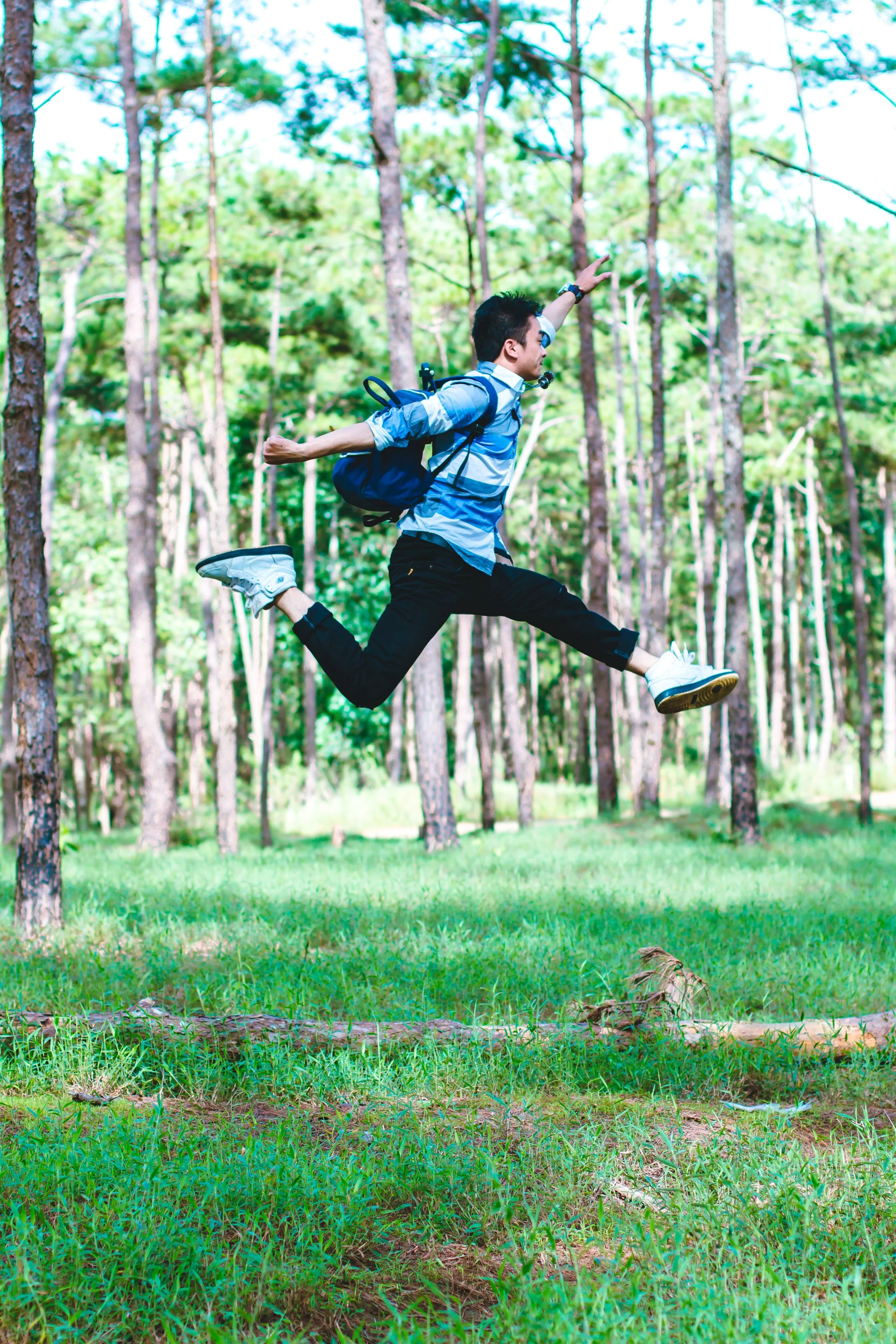 Teenage boy jumping with backpack in forest