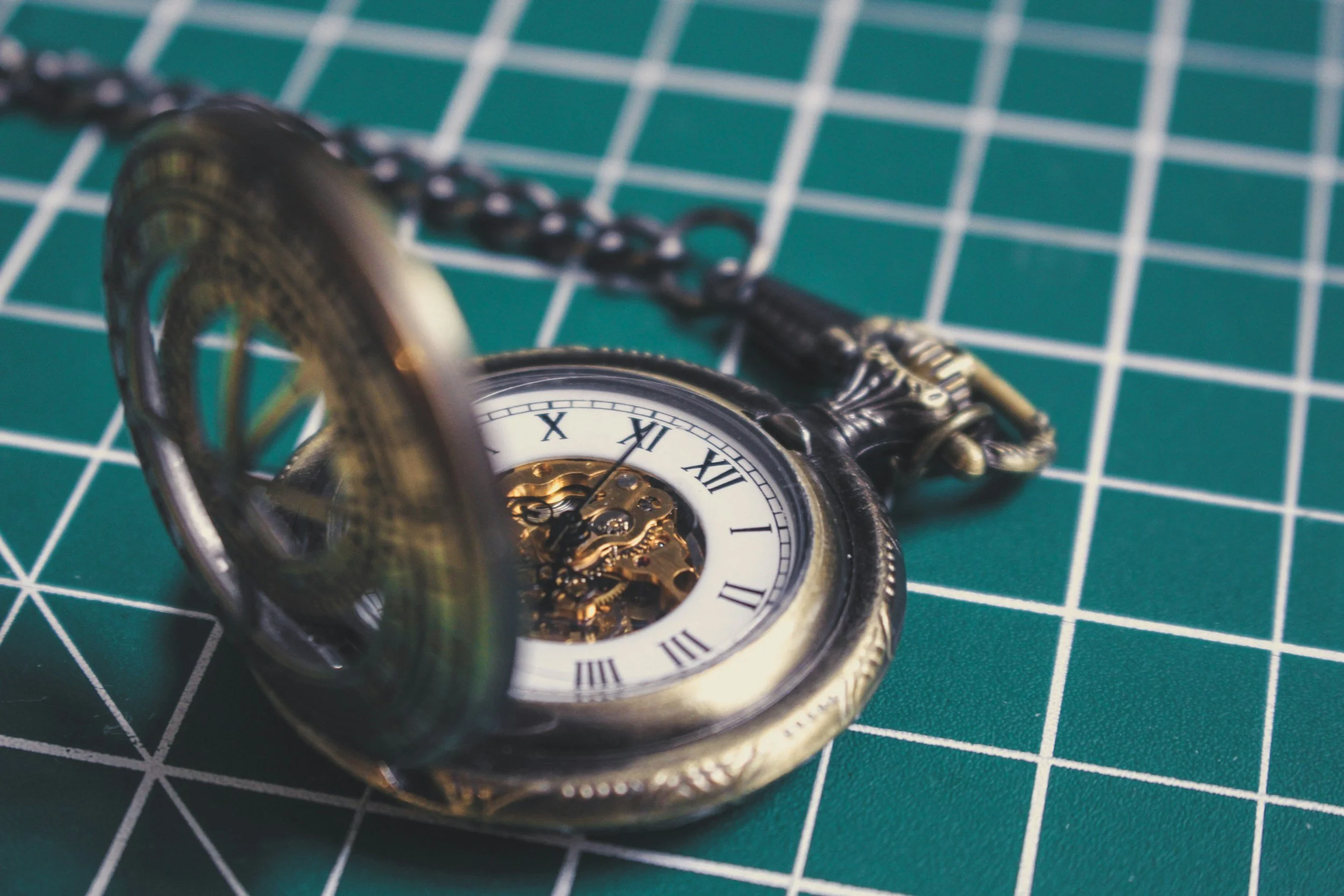 A pocket watch sits on a cutting mat