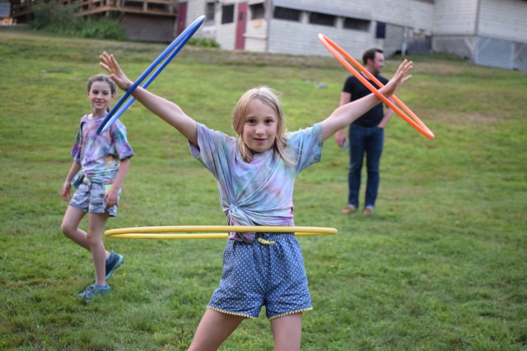 Girl smiles with hula hoops around her arms and waist