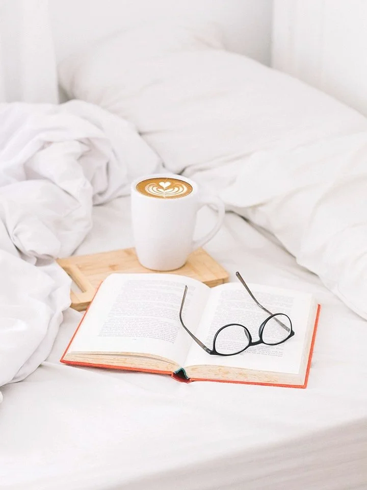 Glenn Gemmell - Publications & Book Designer; A photograph of a red book, reading glasses on a bed.