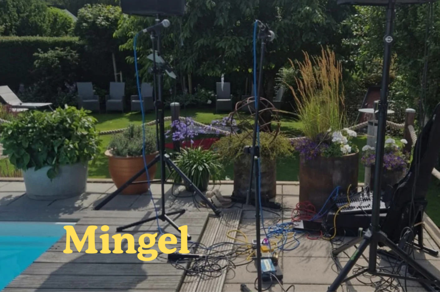 Uteplats med musikutrustning, mikrofonstativ, kablar och ljudutrustning, omgiven av blomkrukor och träd i trädgård.