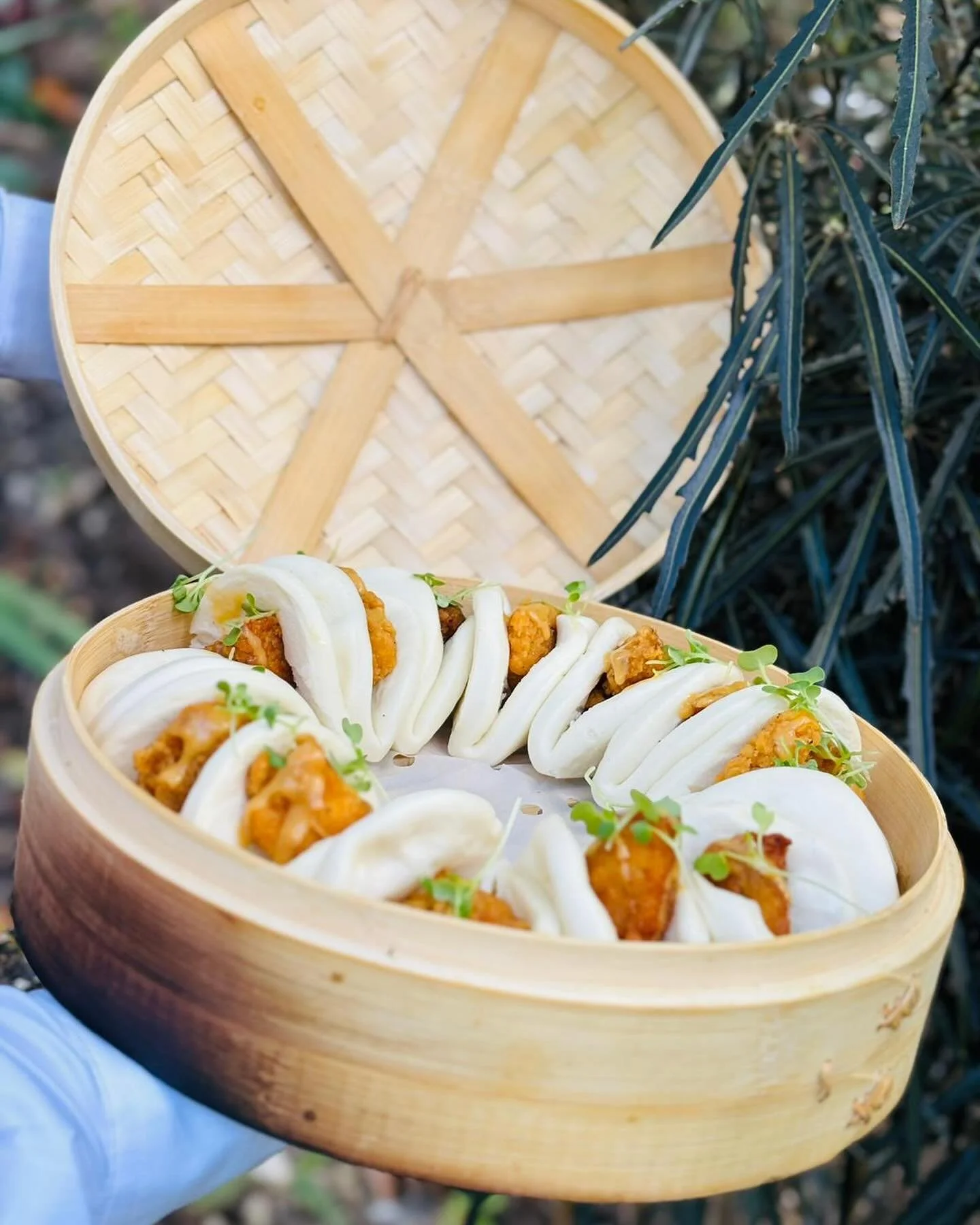 Steamed bao buns with fillings in a bamboo steamer basket.