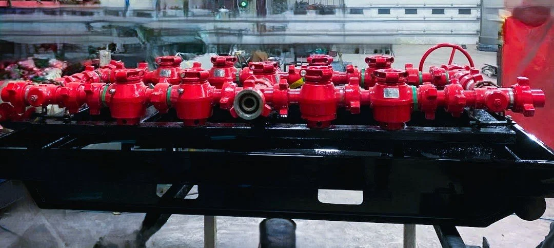 A large black tray holding multiple red fire suppression system components, including valves and connectors, on a workbench in a shop. flowback manifold