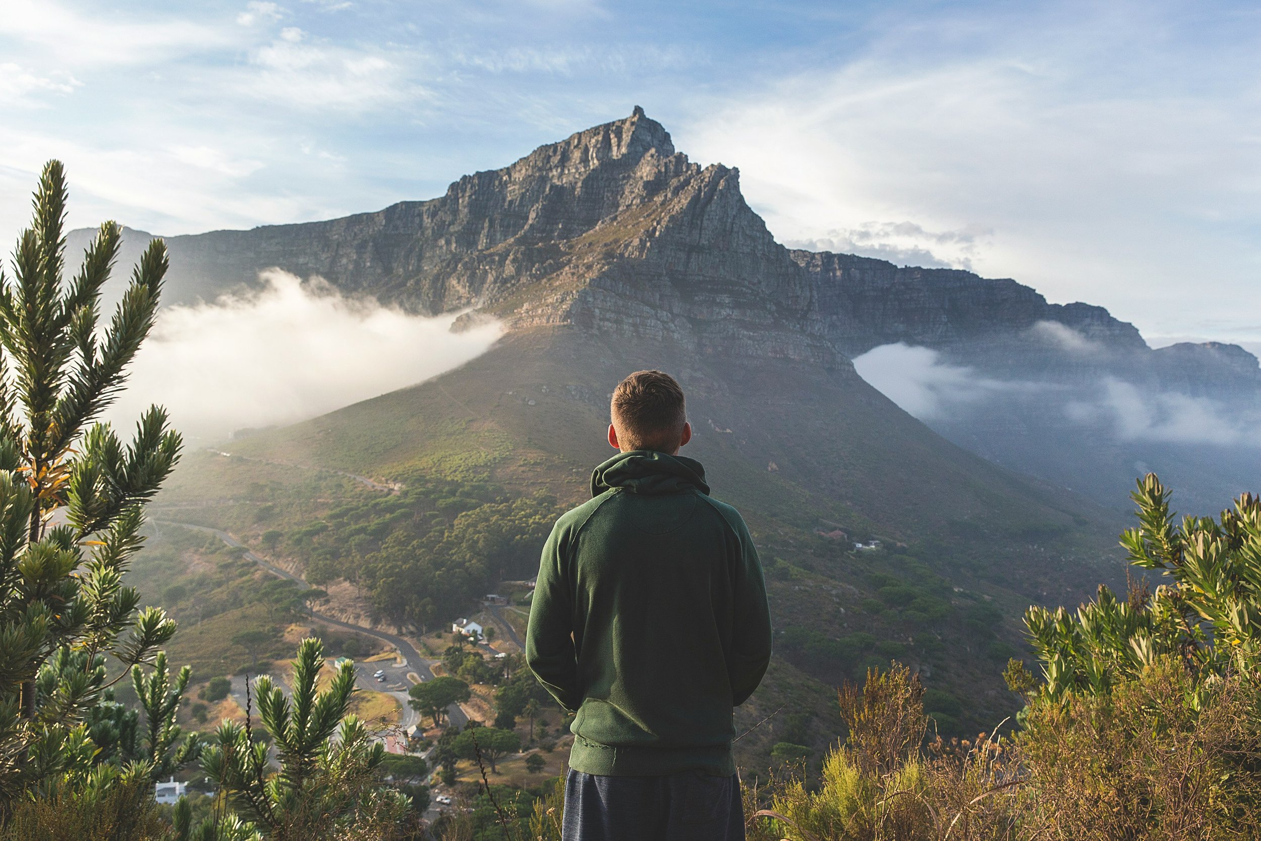 A person facing a vast view of a mountainscape