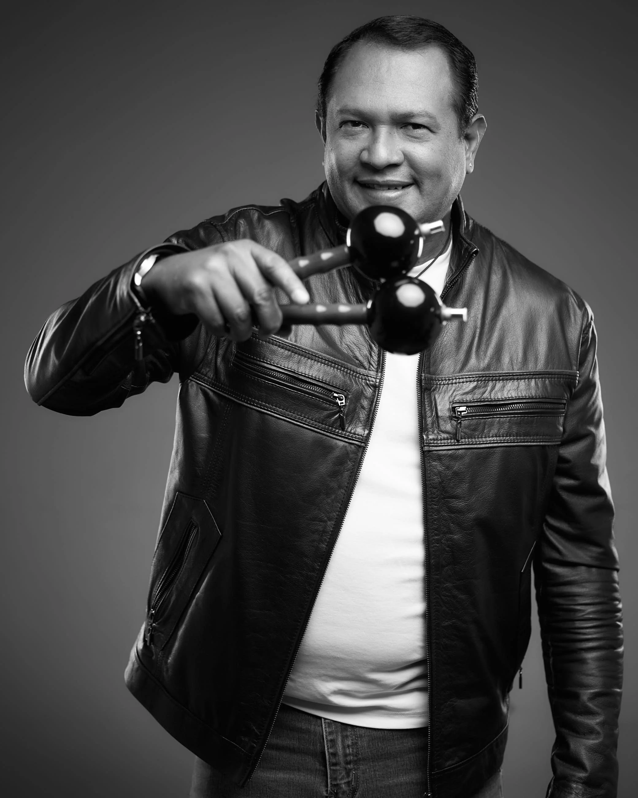 Man in leather jacket holding a Molotov cocktail, smiling, black and white photo.