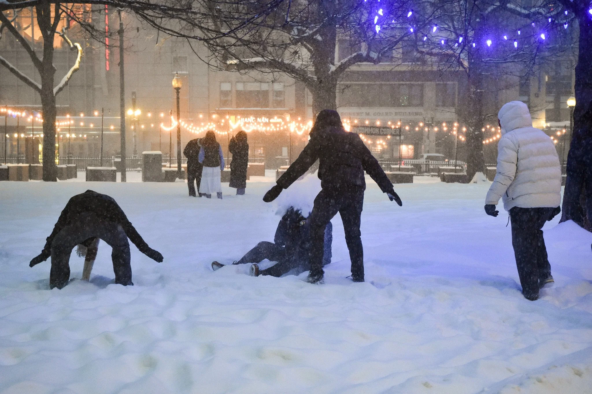 Boston, MA: Jan. 25 -  Friends cover the snow angel maker in snow as they get up. 