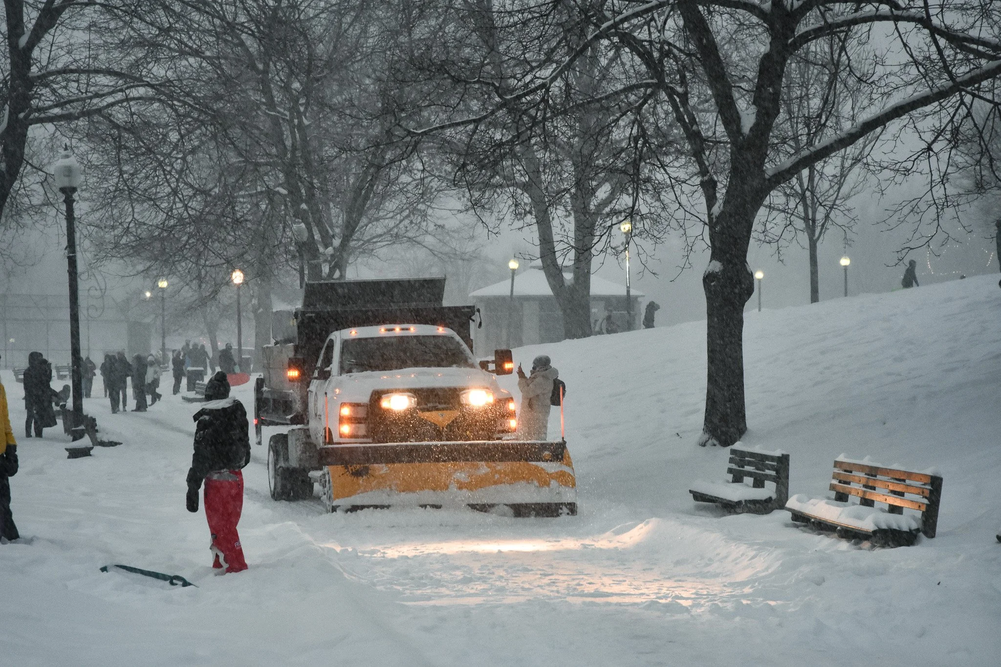 Boston, MA: Jan. 25 -  A snow plow goes through a crowd of people sledding and walking in the Boston Common. 