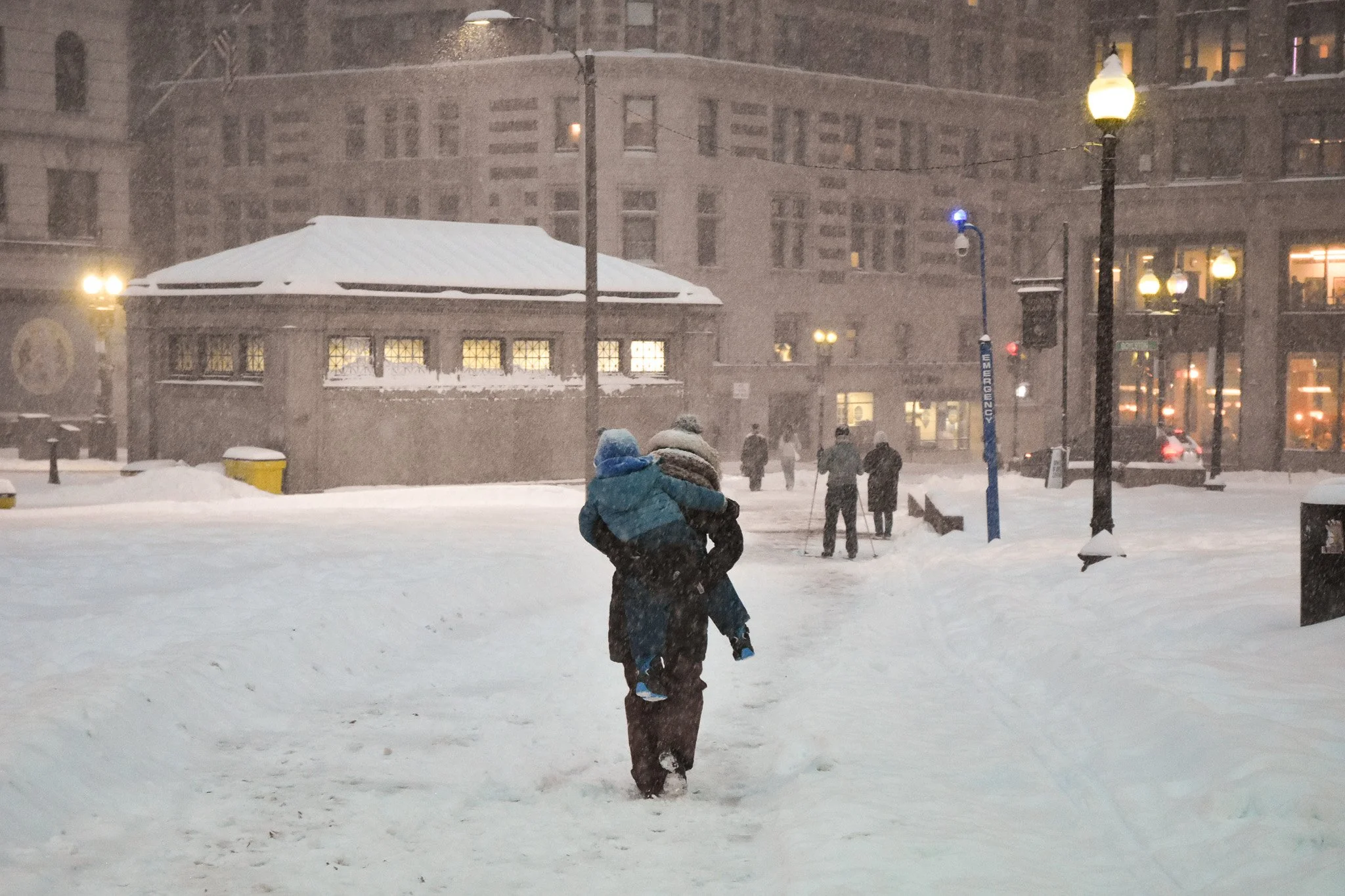 Boston, MA: Jan. 25 -  A mother carries a child on her back, on their way home from a fun-filled day. 