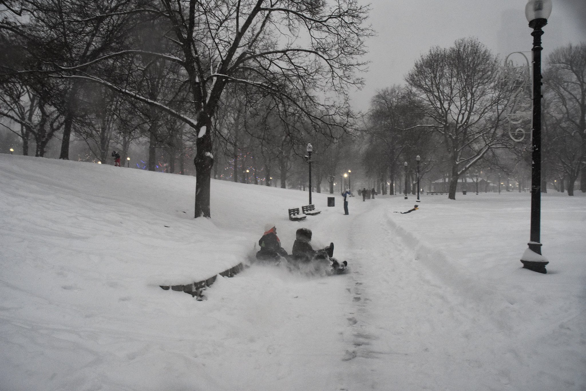 Boston, MA: Jan. 25 -  Two sledders suddenly hit the sidewalk after going over a hidden brick wall. 