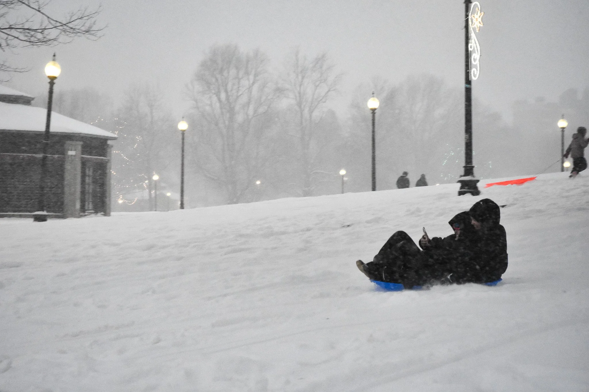 Boston, MA: Jan. 25 -  Two sledders go down the hill, one of them filming the experience. 