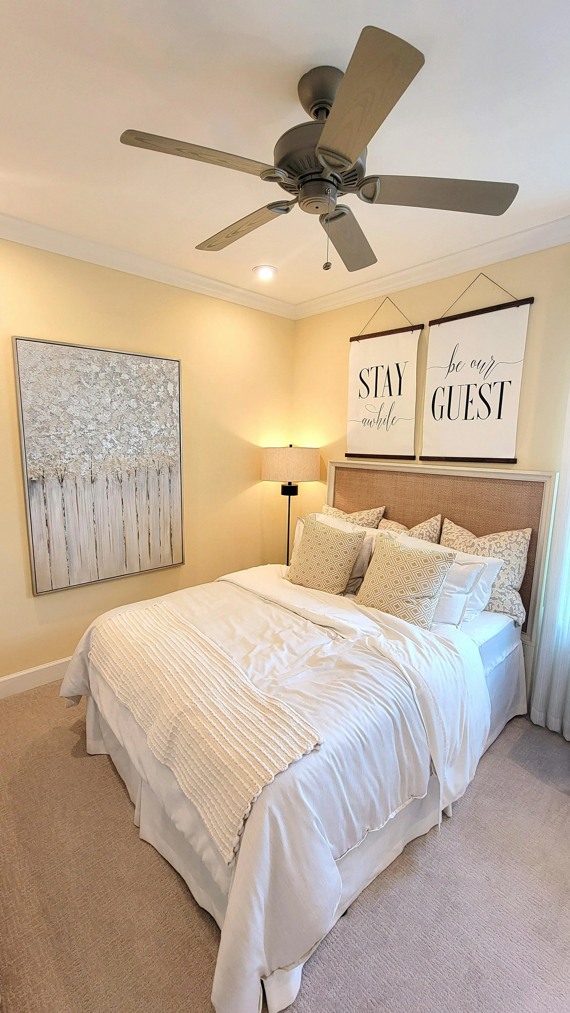 Cozy bedroom with a bed, multiple pillows, a wall art and a ceiling fan