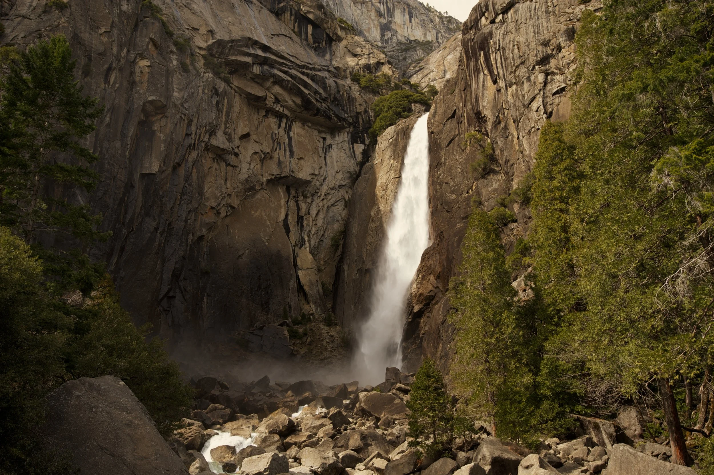 A waterfall cascading down a cliff surrounded by green trees and rocks.