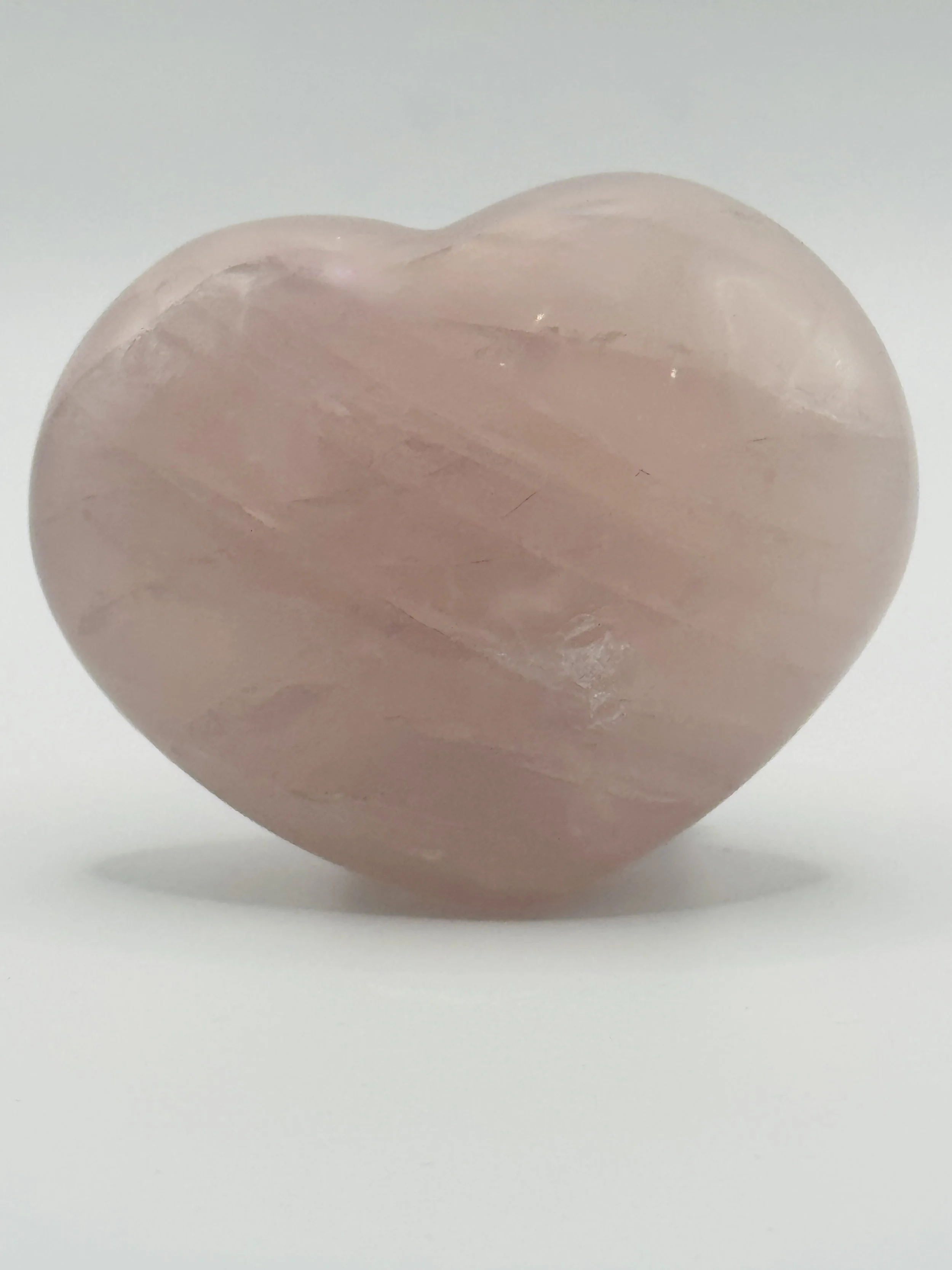 Pink Quartz heart-shaped crystal on a white surface