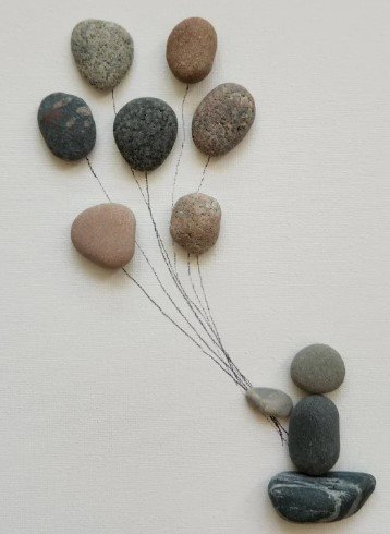 Rocks arranged to resemble balloons tied to a bunch of stones.