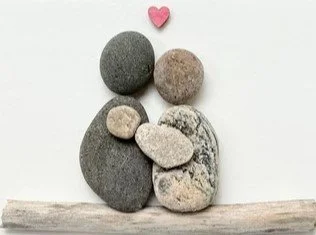 Arrangement of various-sized smooth stones with a small pink heart on top against a white background.