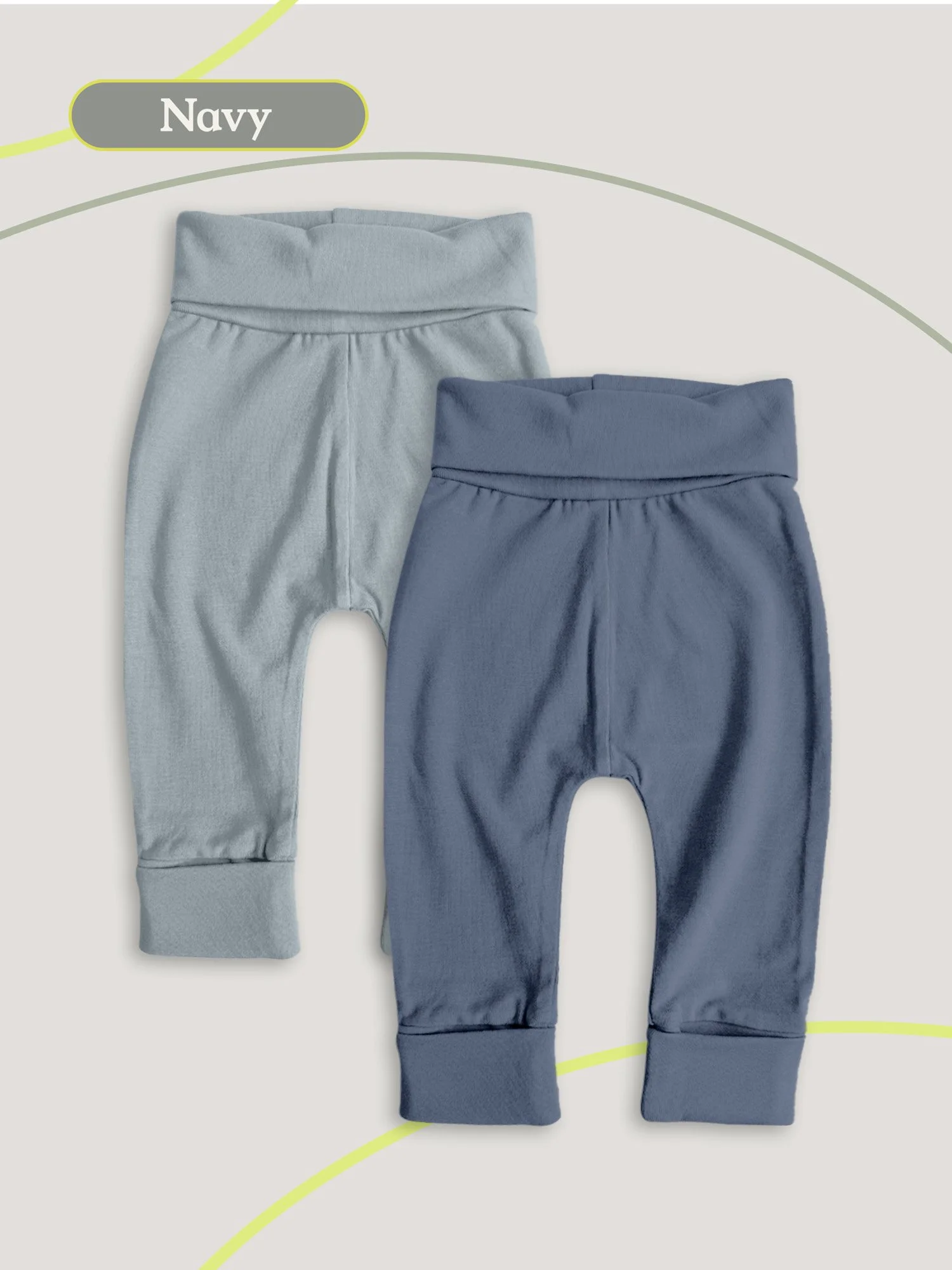 Flat lay of two pairs of baby pants in navy and blue on a neutral background.