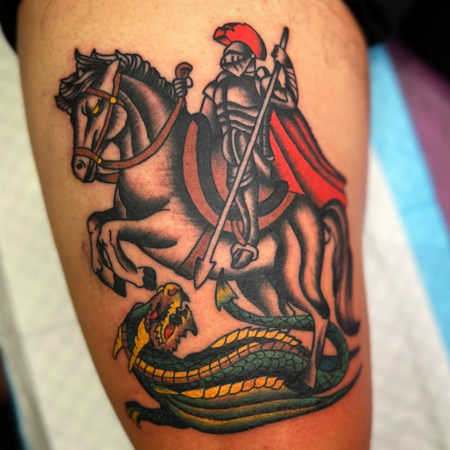 Tattoo of a knight on horseback fighting a dragon.
