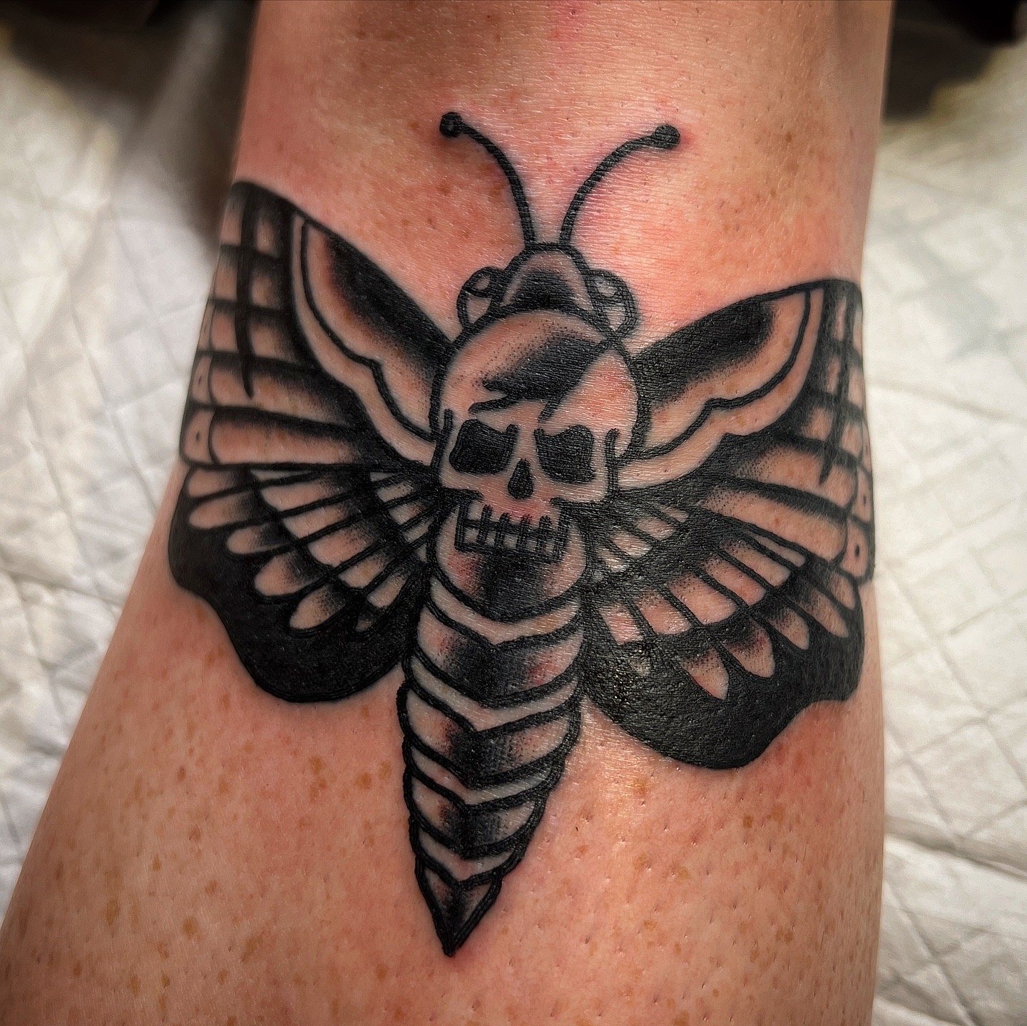 Tattoo of a butterfly with a skull in the center on a person's skin.