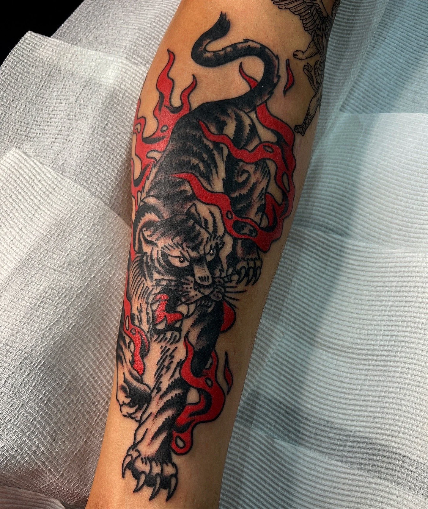 Tattoo of a fierce tiger with red flames surrounding it.