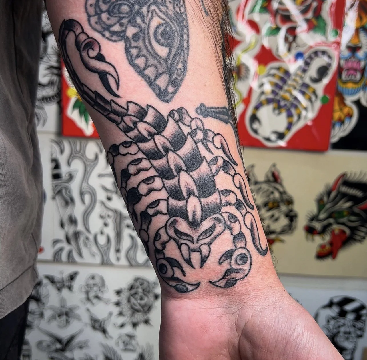 Black and gray tattoo of a scorpion on a person's forearm.